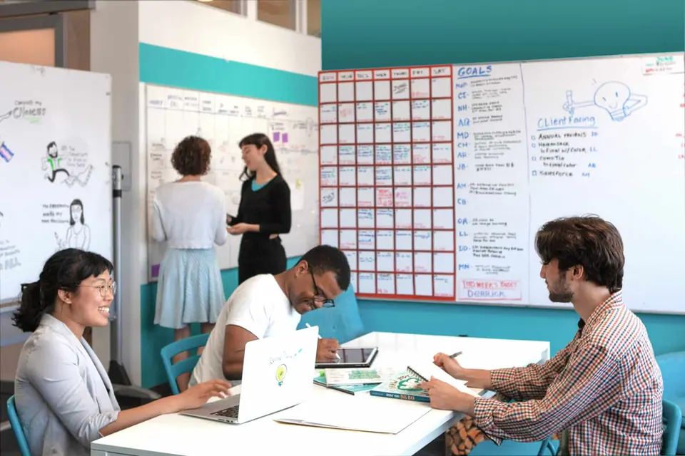 An image of the ImageThink team of visual strategists collaborating at a desk and at a whiteboard.