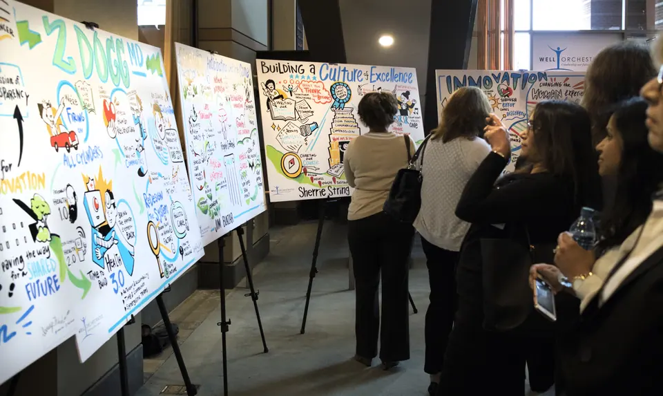 Attendees reviewing visual change management boards at an event.