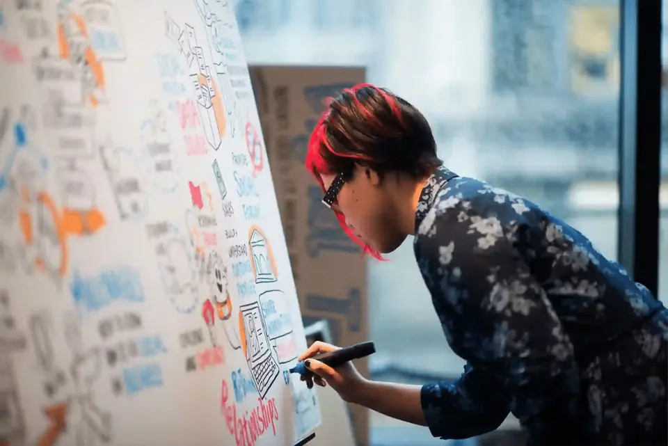 Facilitator sketching visual notes on a whiteboard during a nonprofit workshop.