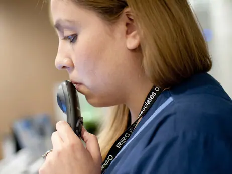 As the doctor examines a patient, medical scribe Connie Gayton records the visit using a microphone tethered to her laptop.