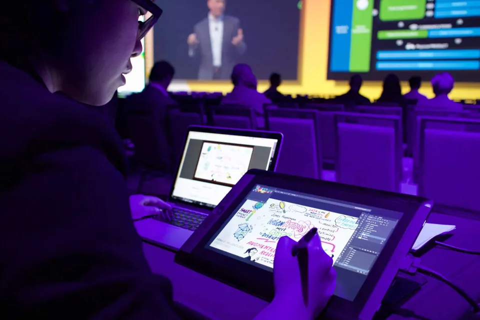 A graphic recorder drawing on a tablet at a technology conference