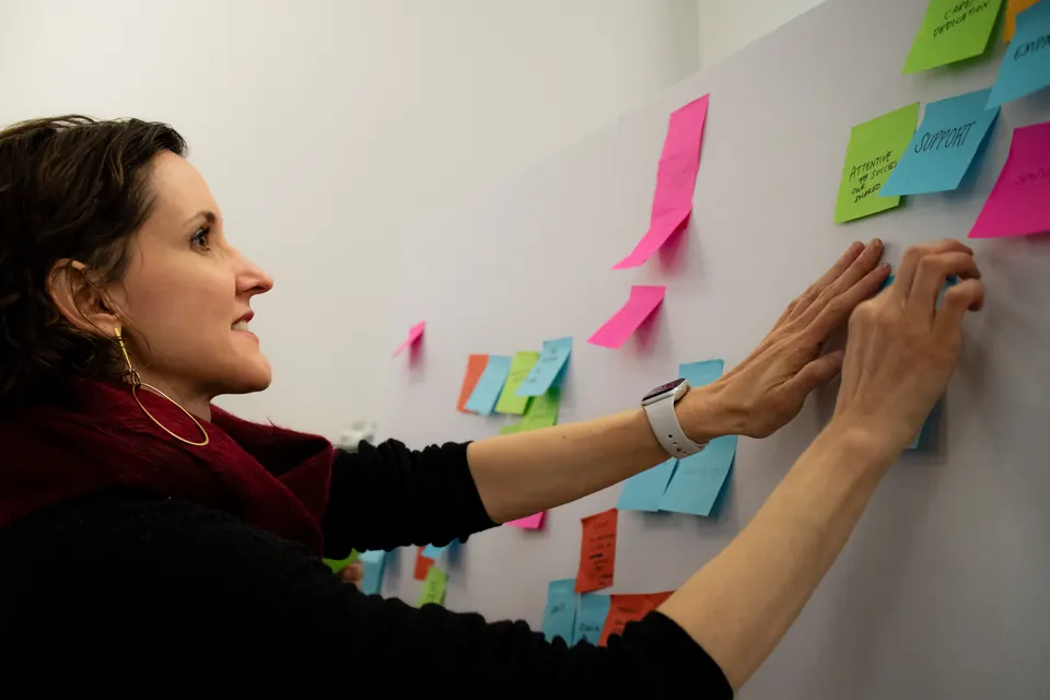 Nora Herting placing sticky notes on a board while facilitating a brainstorm